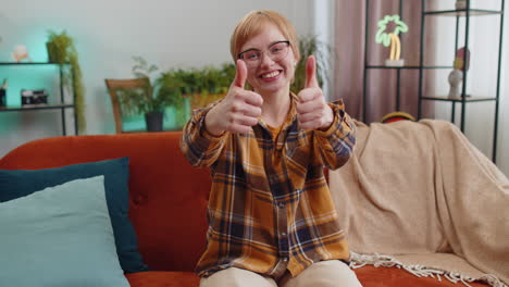 happy young woman looking approvingly at camera showing thumbs up like positive sign good news