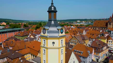 4k aerial drone video of the clock tower and st. johannis kirche church in ansbach, germany with windmill in the distance