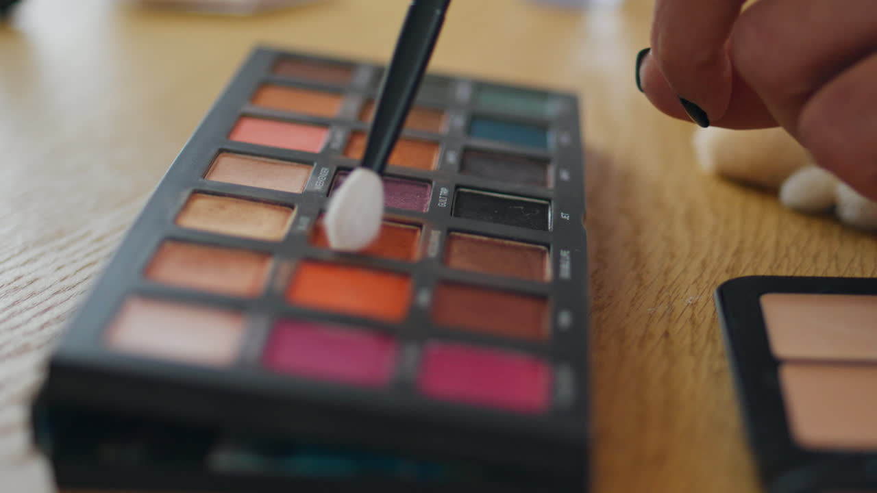 mujer señalando con el dedo la paleta de maquillaje en casa de cerca. niña tomando sombras para los ojos