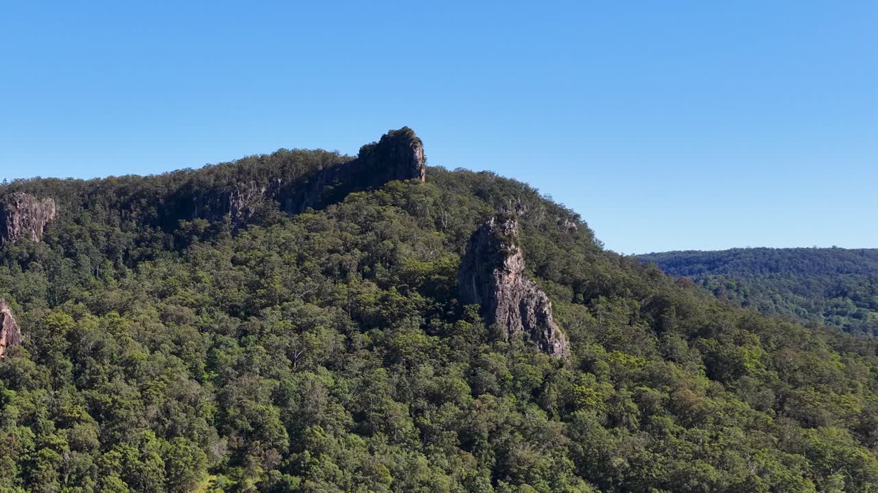 Aerial footage captures the lush greenery and unique rock formations of Nimbin Rocks under clear blue skies