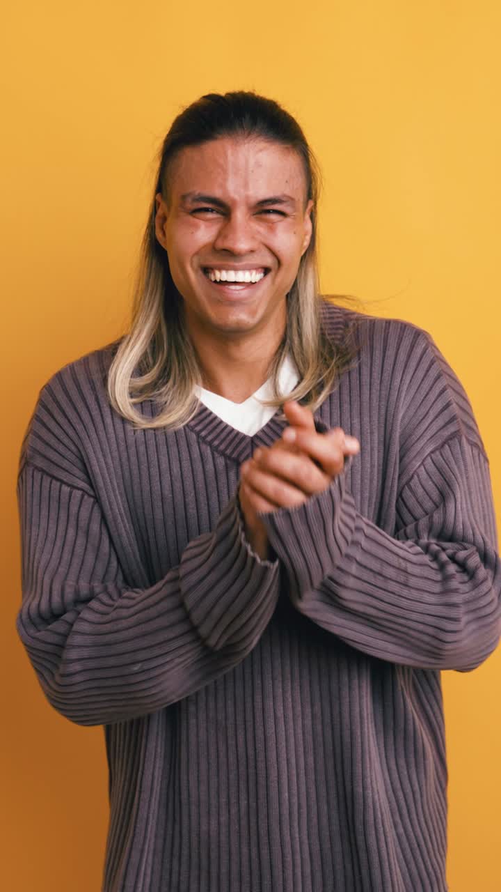 Giovane uomo felice che ride e applaude in studio