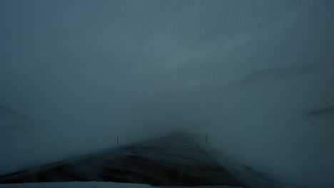 slow motion driving pov as windy snow covers asphalt road in iceland