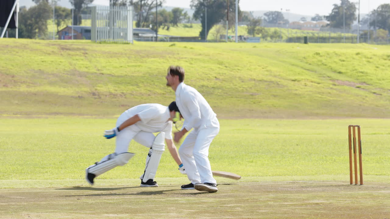 Two teams of multiracial male cricket players and male umpire playing cricket on pitch