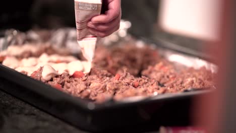 preparing a meat-based dish with cheese sauce