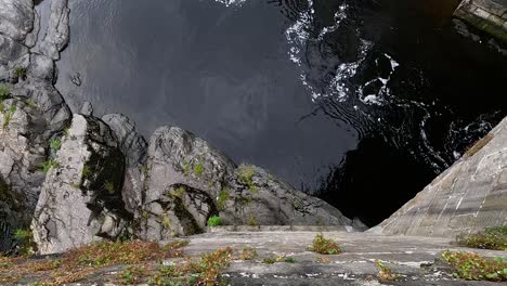 water flows between rocks and a stone wall