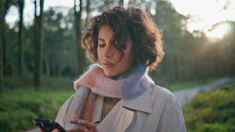 casual woman browsing mobile phone in sunny park closeup. portrait brunette
