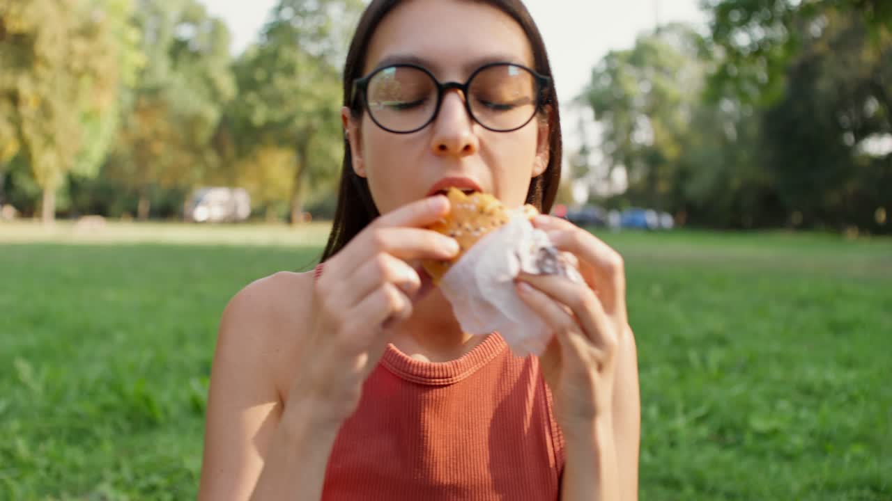 personas comiendo sándwiches en un parque