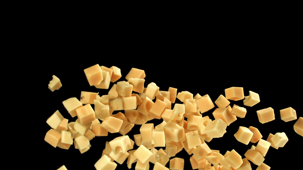 Cubetti di formaggio fresco che cadono al rallentatore su sfondo nero