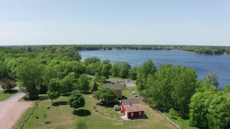 Wide-panning-aerial-shot-of-a-historical-Swedish-immigrant-house-on-the-lake-in-Lindstrom,-Minnesota