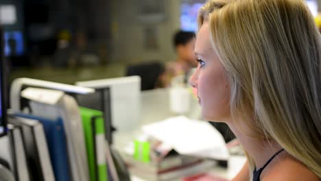 Pretty-blond-woman-at-desk-staring-off-to-the-left-focused,-over-the-shoulder