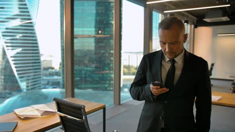 boss standing near window in loft room and writing sms