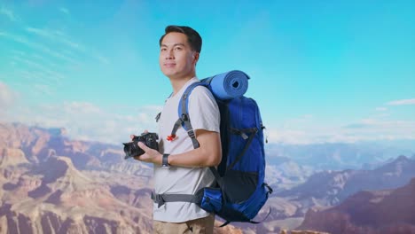 Side View Of Asian Male Hiker With Mountaineering Backpack Smiling And Holding A Camera In His Hands Then Looking Around While Traveling At The Top Of Mountain