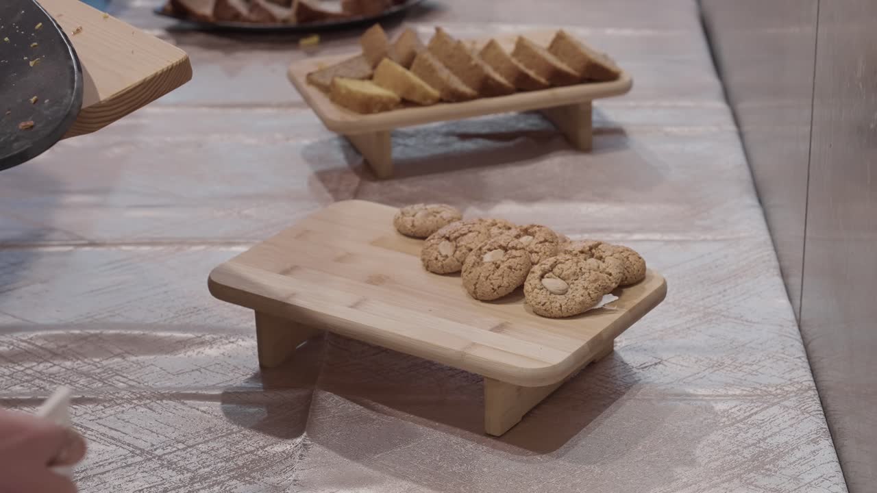 mano cogiendo una galleta de una bandeja de madera en un buffet informal