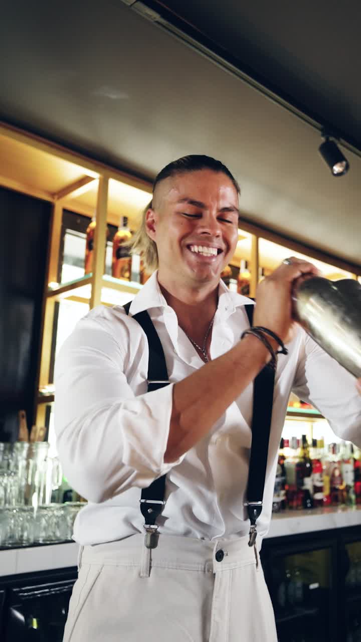 Barman felice che agita uno shaker per cocktail in un bar