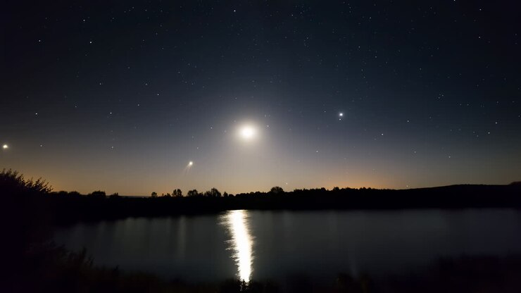 Cielo notturno con luna e stelle che si riflettono nell'acqua