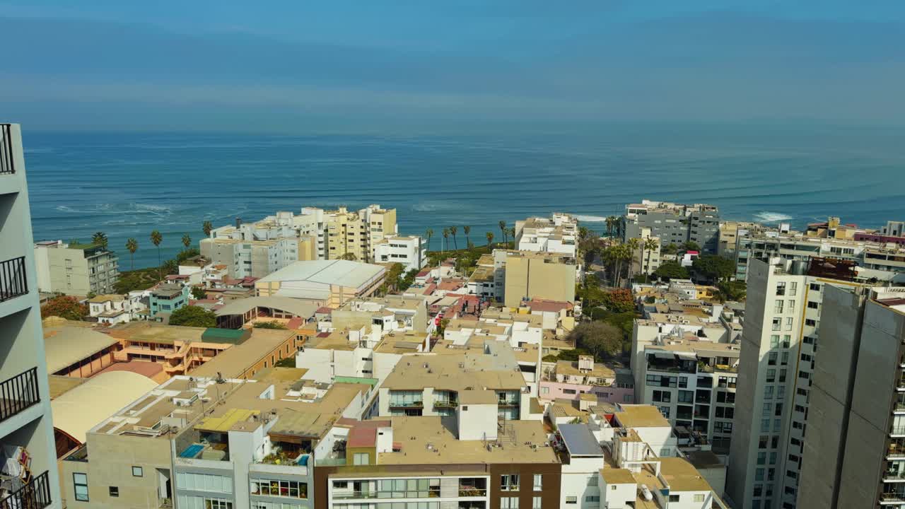 Highrise apartment with ocean establishing balconies, rooftops below and bright blue water in Lima Peru