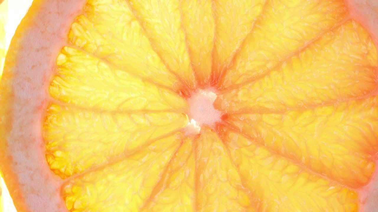 Rotazione dall'alto di una fetta d'arancia su sfondo bianco, fetta trasparente di pompelmo fresco su sfondo bianco, risoluzione 4K