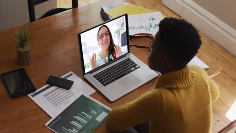 mujer afroamericana que usa una computadora portátil en una videollamada con una colega que trabaja desde casa