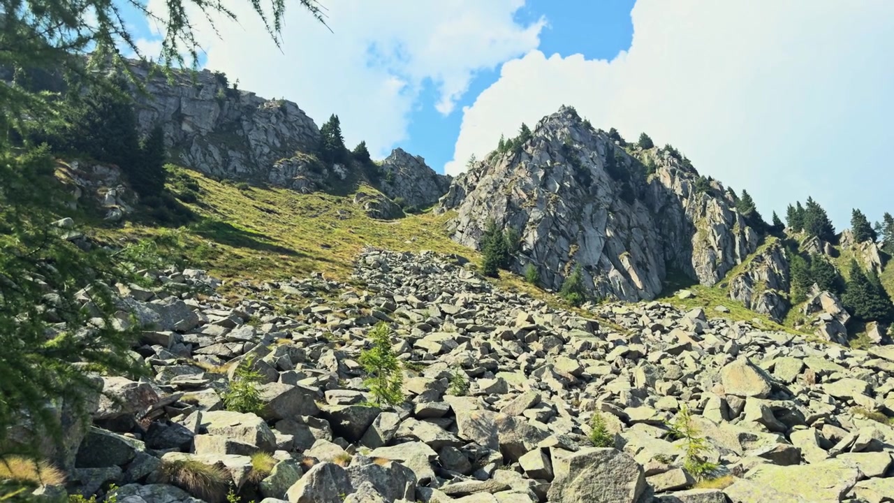 Stenet skråning af et bjerg i Adamello Brenta Naturpark. En solrig sommerdag i de italienske alper med en blå himmel og hvide skyer.