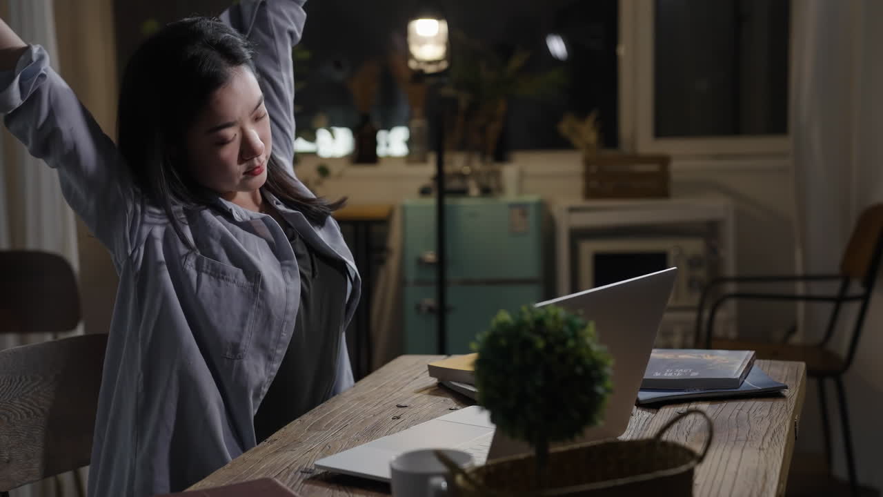 Young woman businesswoman concentrating on her work using laptop computer while sitting at a wooden table late at night in office