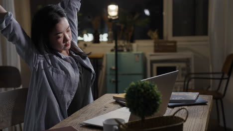 young woman businesswoman concentrating on her work using laptop computer while sitting at a wooden table late at night in office