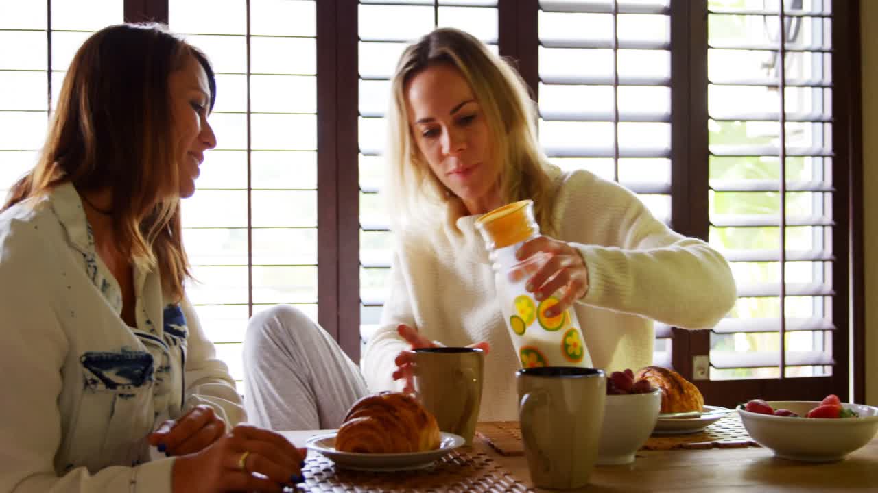 레즈비언 커플이 식탁에서 술을 마시고 있습니다.