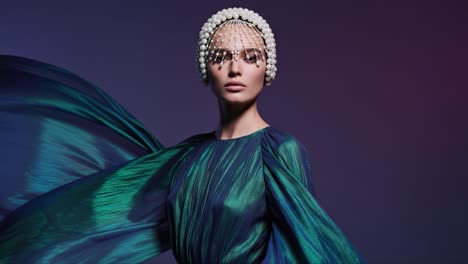 stunning fashion statement: a model showcases a vibrant dress with flowing sleeves and intricate headpiece against a gradient background