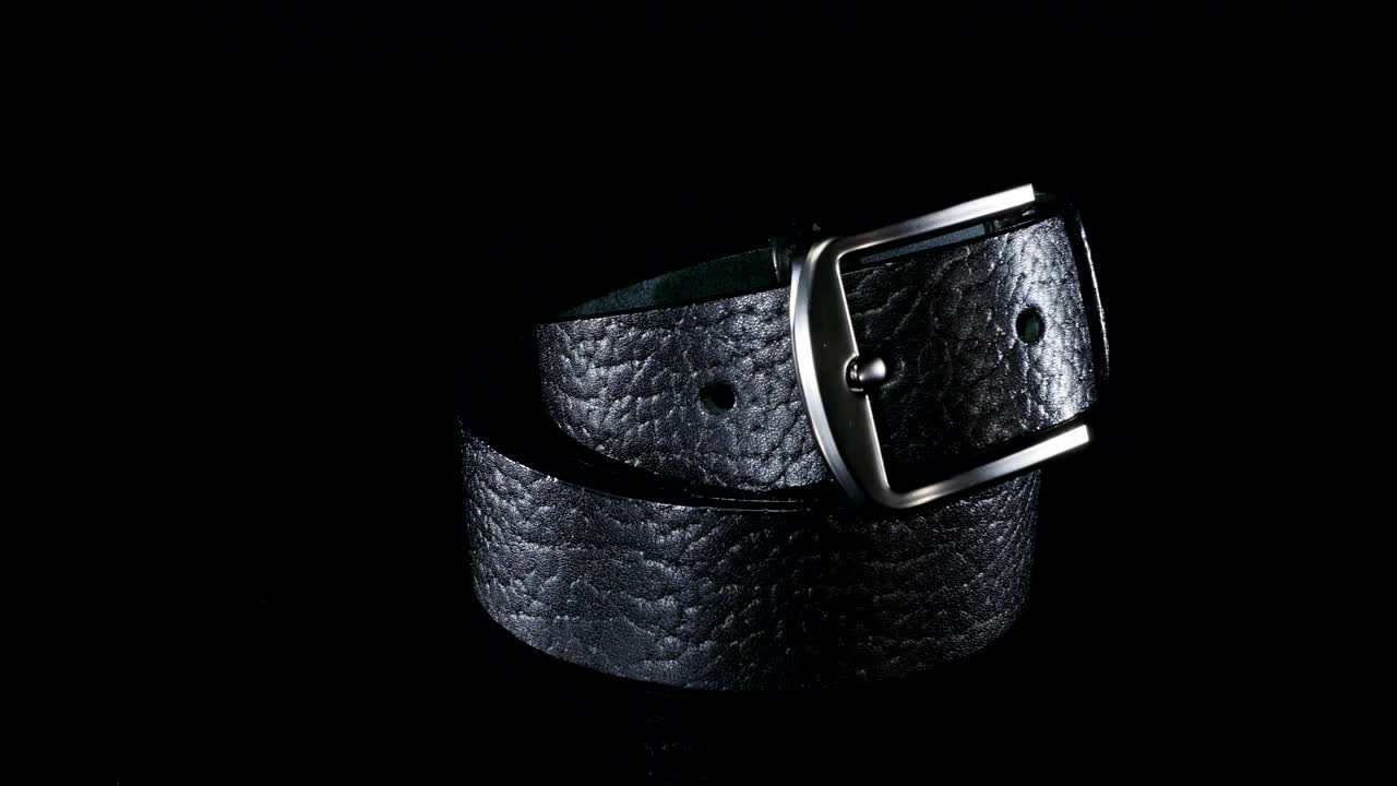 검은색 남성의 벨트는 검은색 배경에 회전합니다.