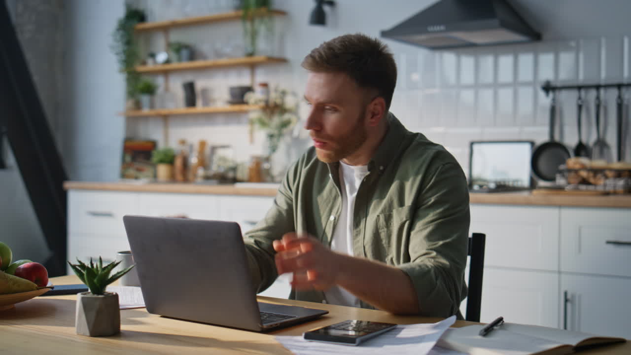 Worried man calculating loss at home office at laptop. Frustrated accountant