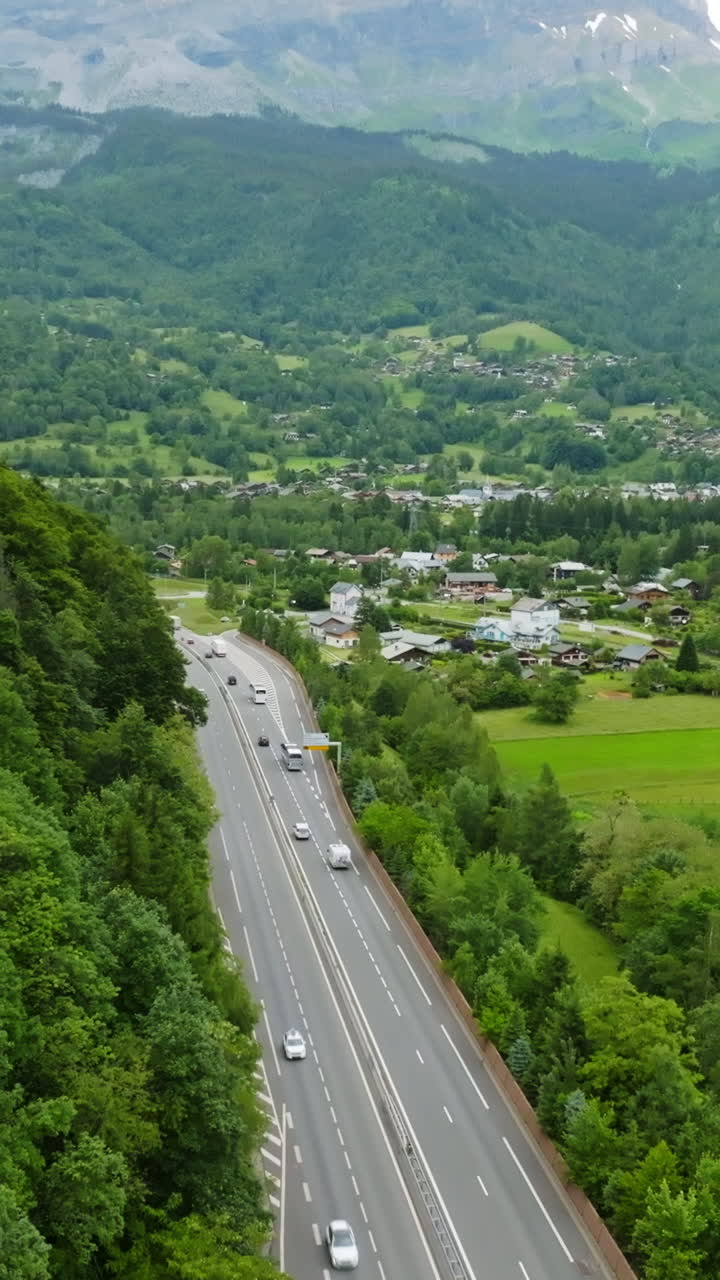 Vertical drone shot of traffic on road N205 and the Servoz village, in France