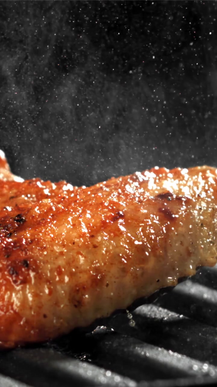 Nærbillede af saftigt kød, der syder på en varm grill.