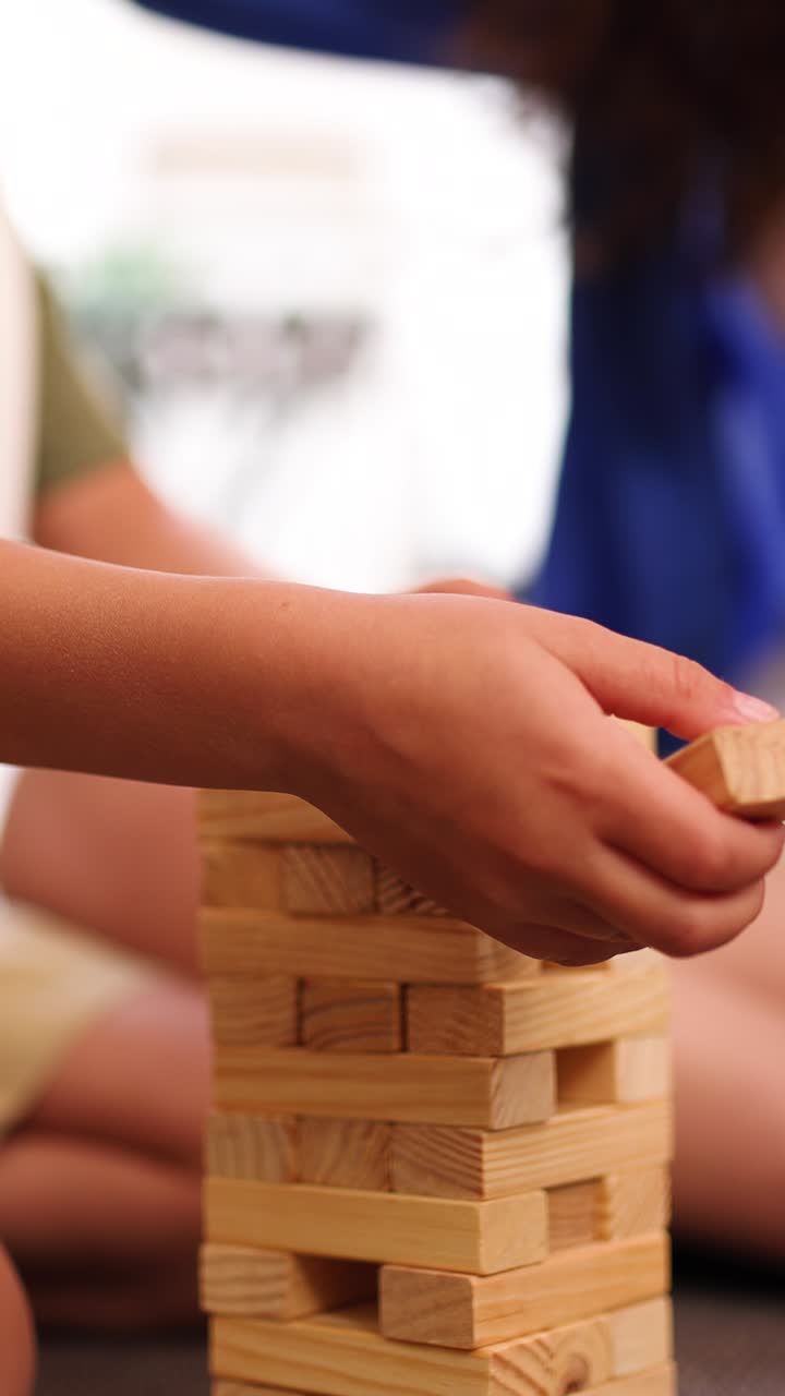 Girl carefully removing wooden block from tower