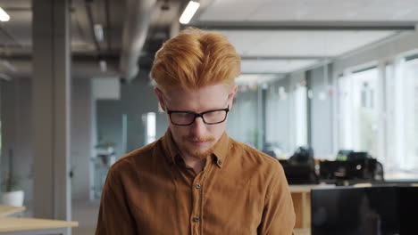 red-haired man walking along office