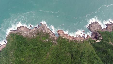 aerial view of a jagged rock island, surrounded with lush green nature and hong kong bay water