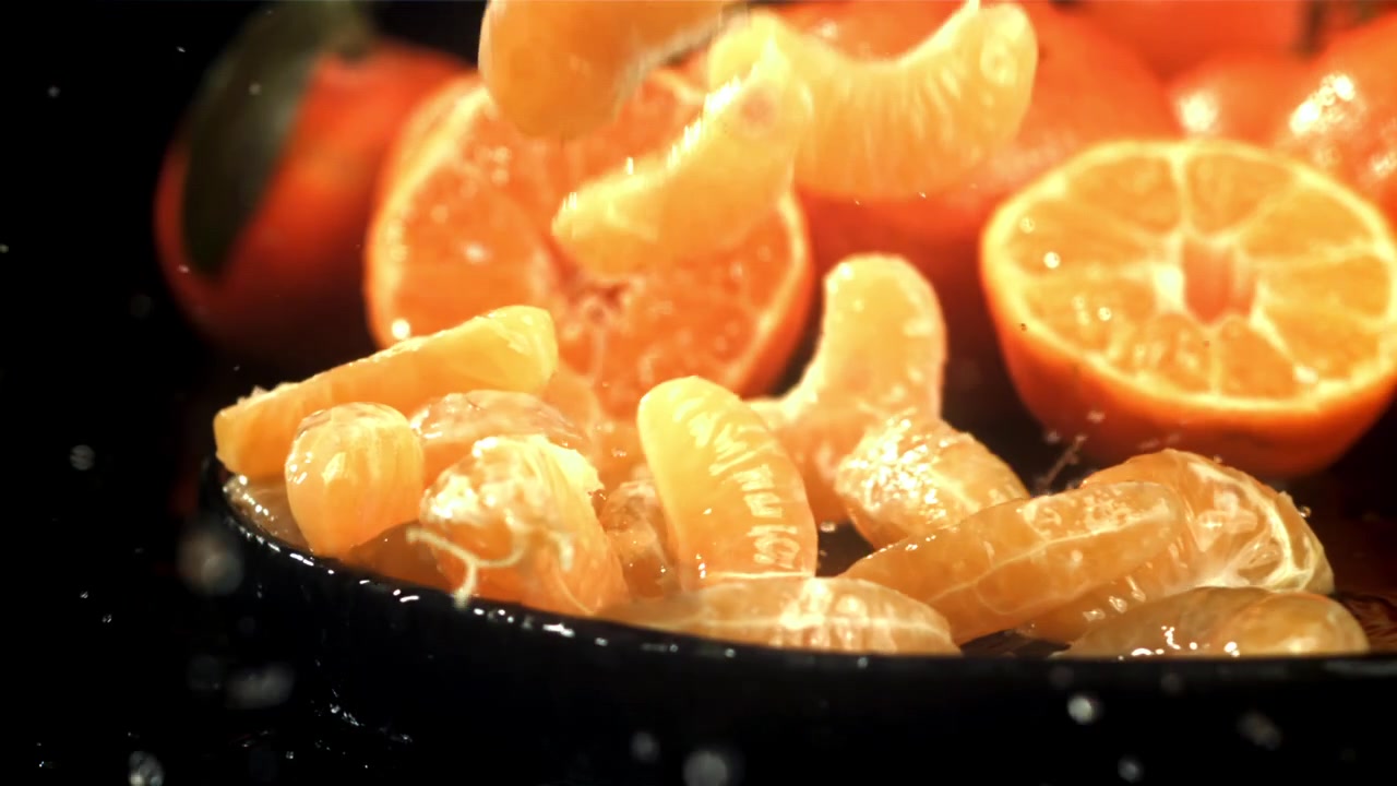 Gomos de Tangerina Fresca Caindo em um Prato Preto em Câmera Lenta