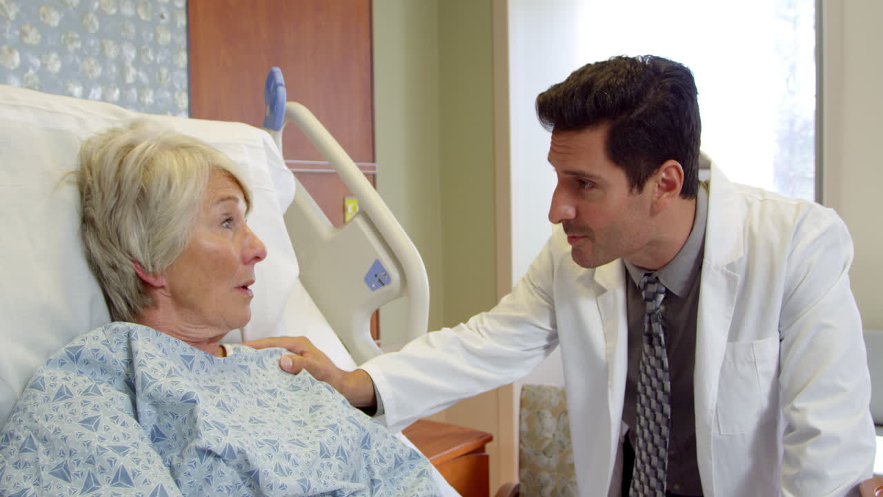 Doctor Talks To Senior Patient In Hospital Bed Shot On R3D