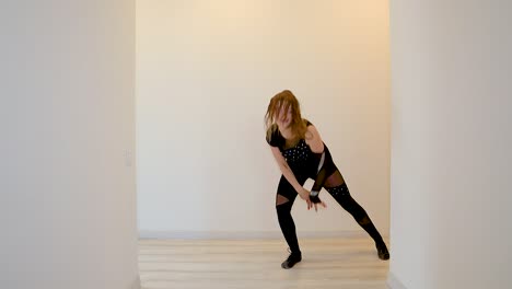 young caucasian female dancer performing a dance routine in slow motion wearing a black outfit