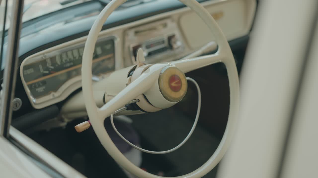 Primo piano del volante di un'automobile retrò con indicatori analogici all'interno di un'auto d'epoca