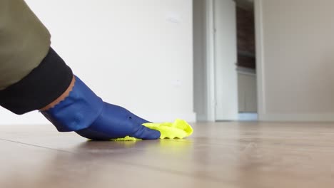 person in blue gloves cleaning wood floor