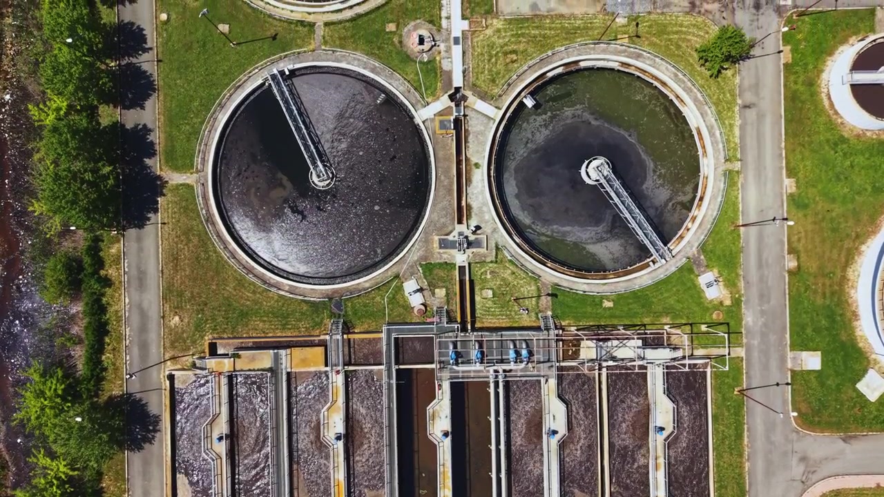 Water plant overview. Sustainable wastewater treatment visuals. Aeration lanes and clarifiers in use. Efficient treatment facility with green surroundings and energy focus