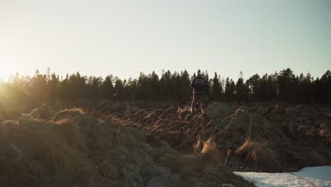 a man with his domestic dog pet digging on the ground at sunset