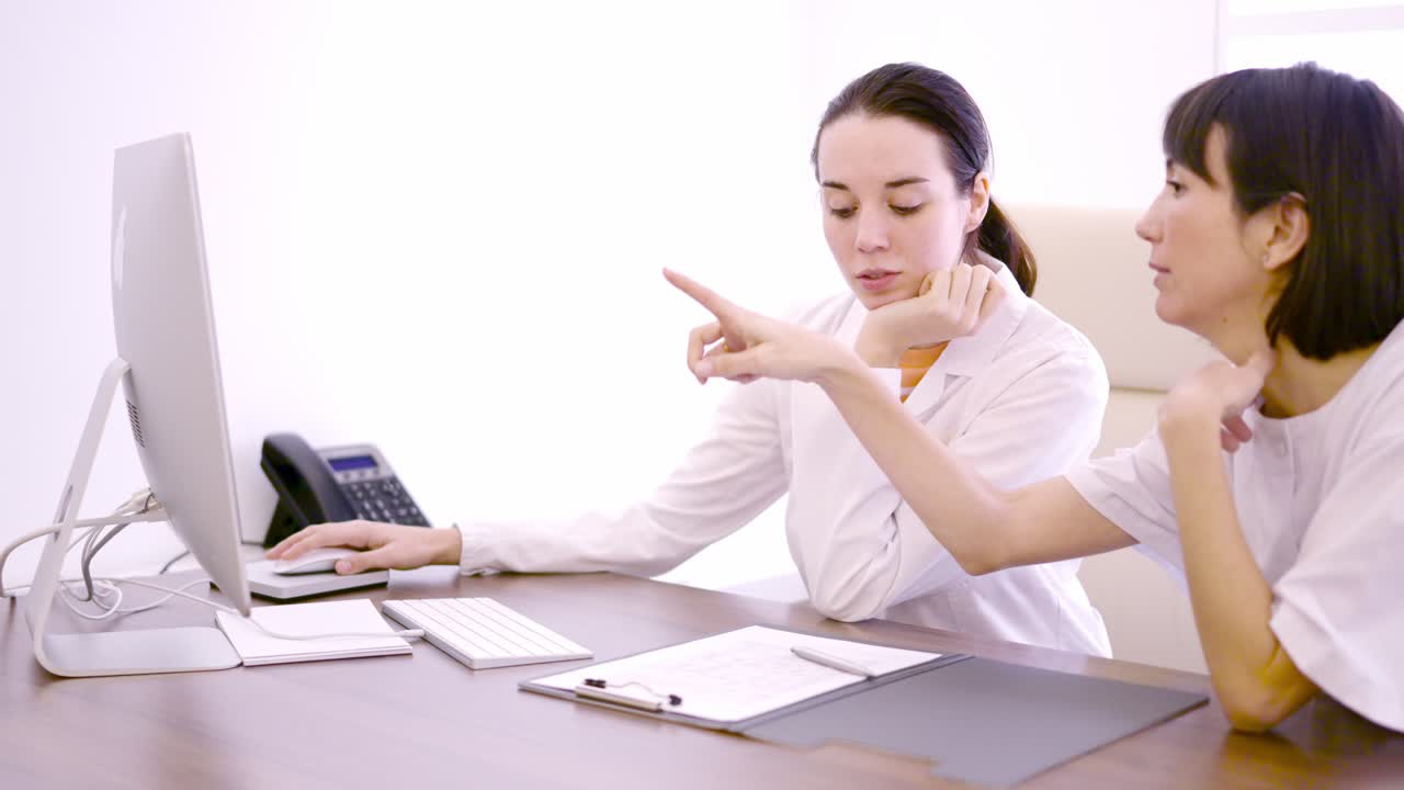 Two doctor talking about medical results while using computer