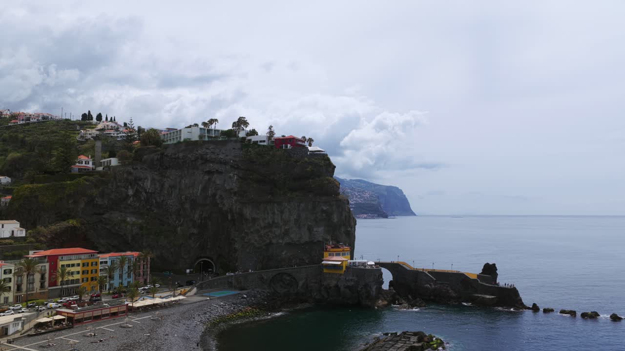 Aerial view of Ponta do Sol, a picturesque village nestled on the coast of Madeira Island, Portugal, showcasing its colorful buildings and unique rock formations. Pull Back Shot