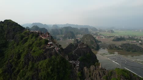 mua cave viewpoint and statue of lying dragon with people enjoying view in ninh binh vietnam at sunset - establishing aerial drone dolly back shot