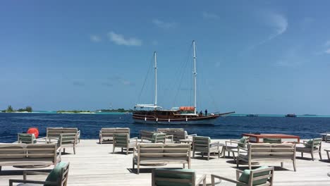 4k video of a traditional sailing ship passing by an island in the maldives filmed from a seaside restaurant