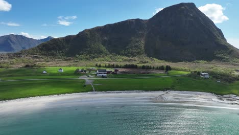 beautiful summer view at hov beach in gimsoy, lofoten, showing sand, farm and hoven mountain