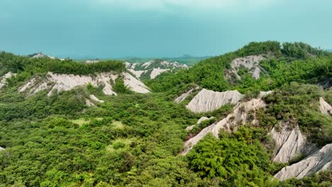 aerial flyover 田寮月世 tianliao moon world with green mountains during foggy day, taiwan