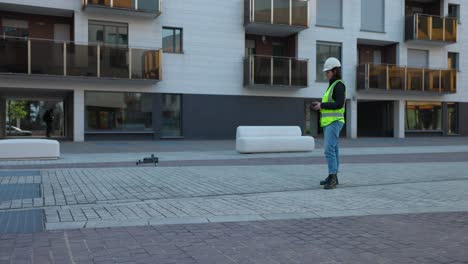 engineer in safety vest and helmet controls drone for photogrammetry by flying it off ground