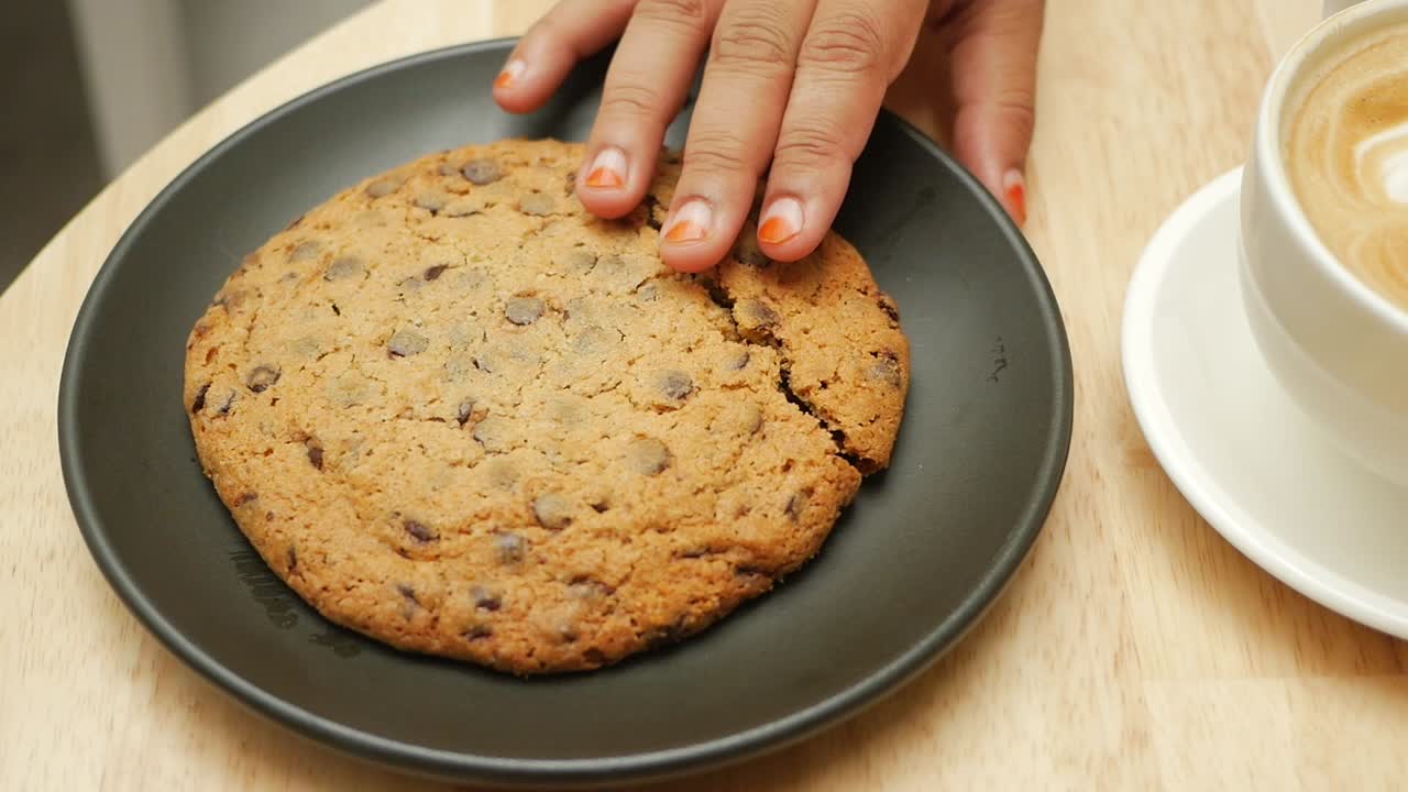 Woman eating chocolate chip cookie and drinking coffee