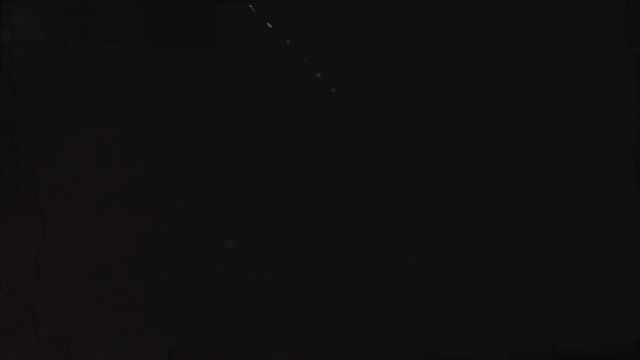 el efecto a cámara lenta de un tomate cereza giratorio que cae sobre el agua, esparciendo aerosol. tomate cerezo único sobre un fondo negro